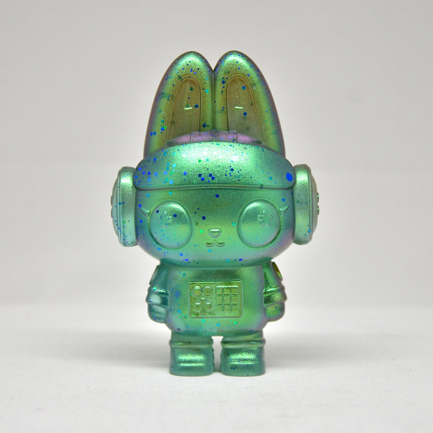 Iridescent green and blue toy figure on a white background